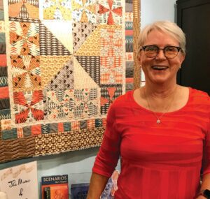 Nancy Sojka, co-founder of the Northeast Iowa Quilters Guild, stands in front of a hanging quilt